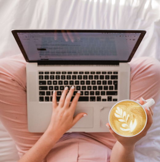 Woman drinking coffee and working in front of a laptop