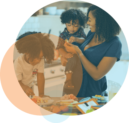 A Black woman holding a kid & another kid is getting ready to eat his meal