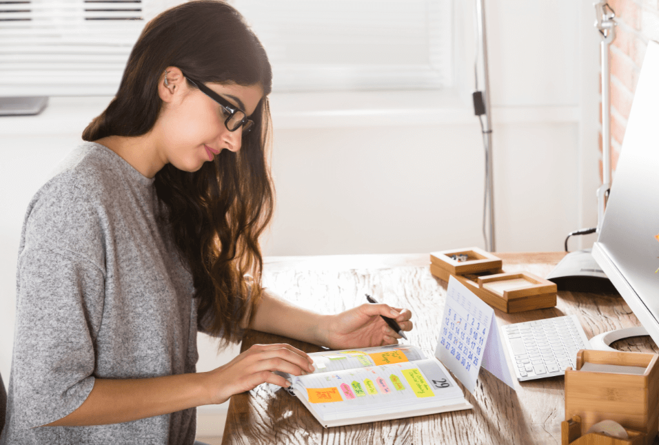 University student sitting in her dorm room, looking at her calendar and planner while considering the best time to schedule a psychoeducational assessment.